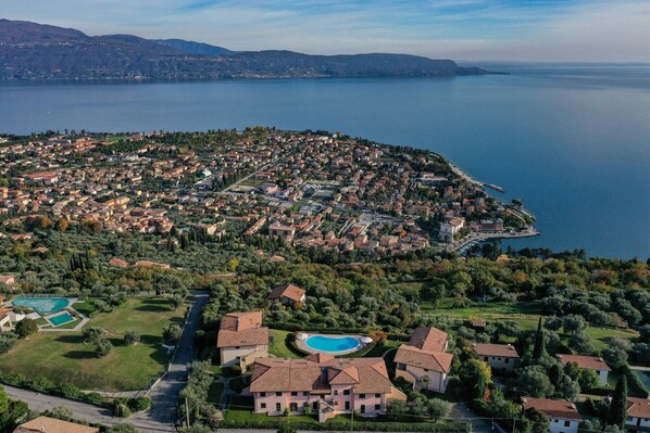 An aerial view of a coastal town with a dense cluster of buildings, a marina, and a large body of water. - Felicity: with lake view and pool (Toscolano-Maderno)