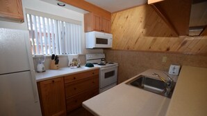 A compact kitchen with wooden cabinets, a microwave, a stove, and a sink. - Beautiful Sleep 6 condominium at CLUB TAHOE, in Incline Village Nevada. (Incline Village)