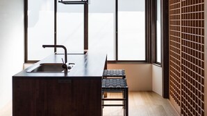 A modern kitchen with a central island, pendant lighting, and large windows providing natural light. - Maana Kyoto (Kyoto)