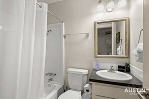 A bathroom with a bathtub, toilet, sink, and a mirror with a gold frame. - HC #102 xxxxxxxxxxxx (Austin)