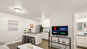 A modern apartment with a kitchen, living area, and a TV displaying streaming services.