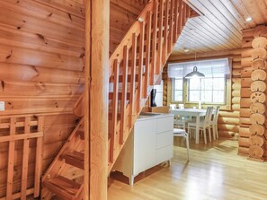 Un interior de madera con una escalera, un comedor y una cocina.