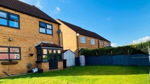 A two-story brick house with a well-maintained lawn, a garage, and a blue fence. - 4-bed House With Private Garden in Barnsley! (Barnsley)