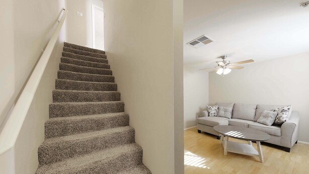 A staircase with carpeted steps leading to a landing, a ceiling fan, a light fixture, a sofa with cushions, and a coffee table. - GATED 2 Bedroom/1.5 Bath Townhome FURNISHED  (Bakersfield)