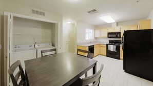A compact kitchen with a dining area, featuring a stove, microwave, oven, and a black refrigerator. - GATED 2 Bedroom/1.5 Bath Townhome FURNISHED  (Bakersfield)