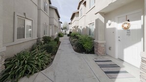 A narrow residential street with houses on both sides, a clear sky, and a wreath on one door. - GATED 2 Bedroom/1.5 Bath Townhome FURNISHED  (Bakersfield)