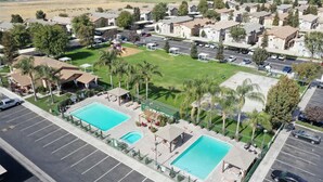 A residential area with two swimming pools, a playground, and a parking lot. - GATED 2 Bedroom/1.5 Bath Townhome FURNISHED  (Bakersfield)