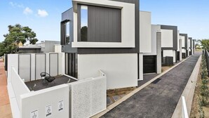 Un moderno edificio residencial con diseño minimalista, que presenta un ventanal central destacado y una serie de puertas numeradas.