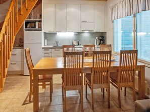 A modern kitchen with white cabinets, a wooden dining table, and chairs.