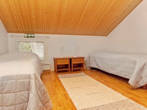 A bedroom with two beds, a desk, and a window.