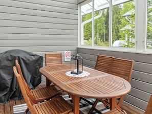 A covered patio with a wooden table and chairs, a grill, and a sign indicating no smoking.