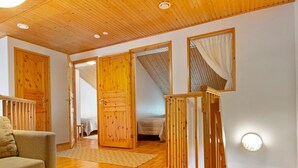 Una habitación acogedora con pisos de madera, un sofá, una cama y una escalera que conduce a otra habitación.