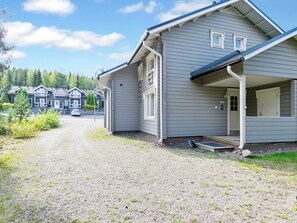 A residential building with a gravel driveway, a covered porch, and a clear view of the surrounding area.