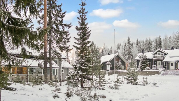 Paisaje nevado con un albergue que cuenta con un amplio porche y varias construcciones.