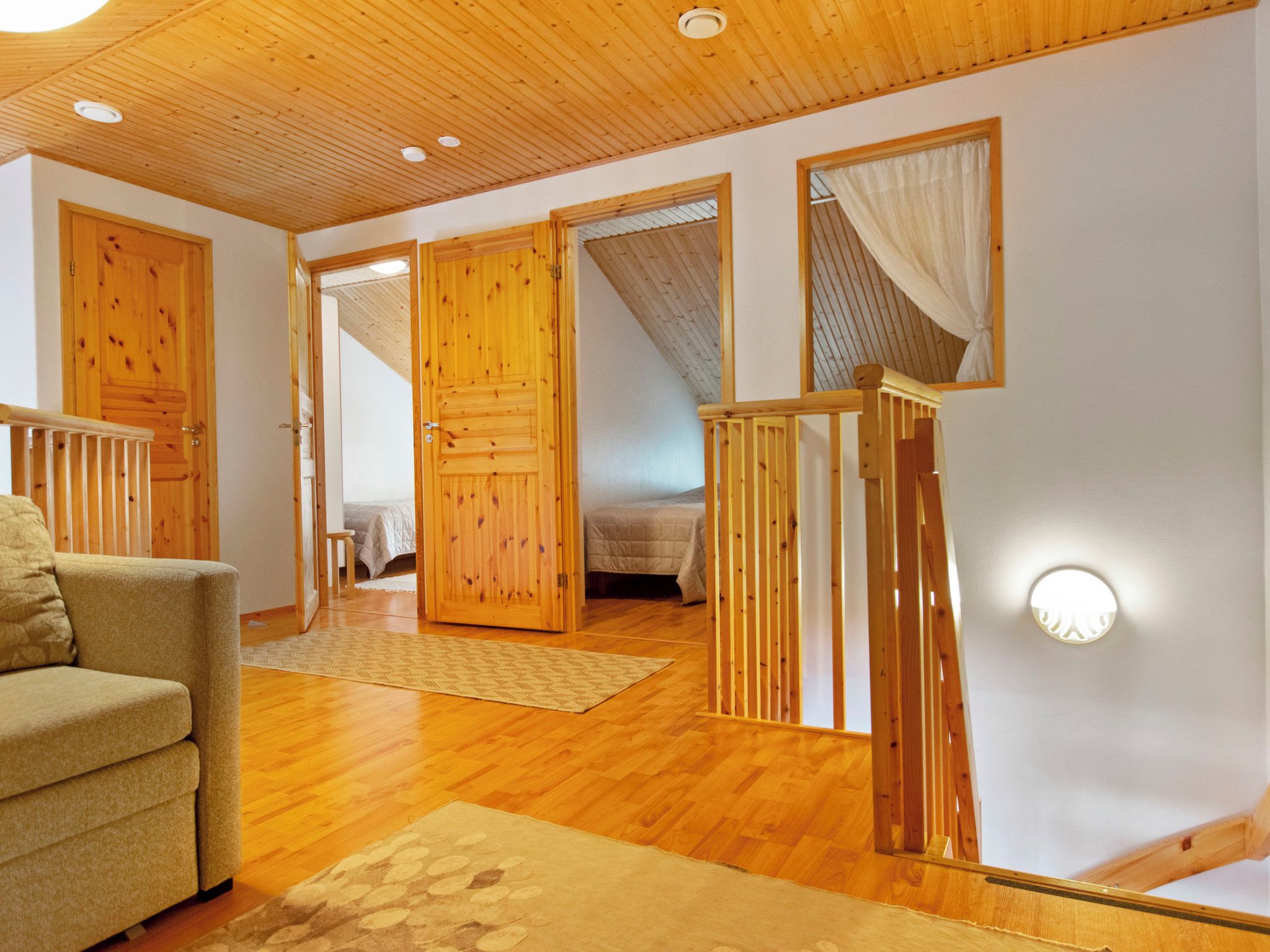 Une pièce avec un plancher en bois, un canapé, un lit et un escalier doté de rampes en bois.