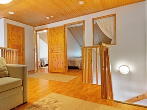 Una habitación con suelo de madera, un sofá, una cama y una escalera con barandilla de madera.