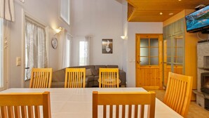 Un comedor con una mesa y sillas de madera, un sofá y un televisor al fondo.