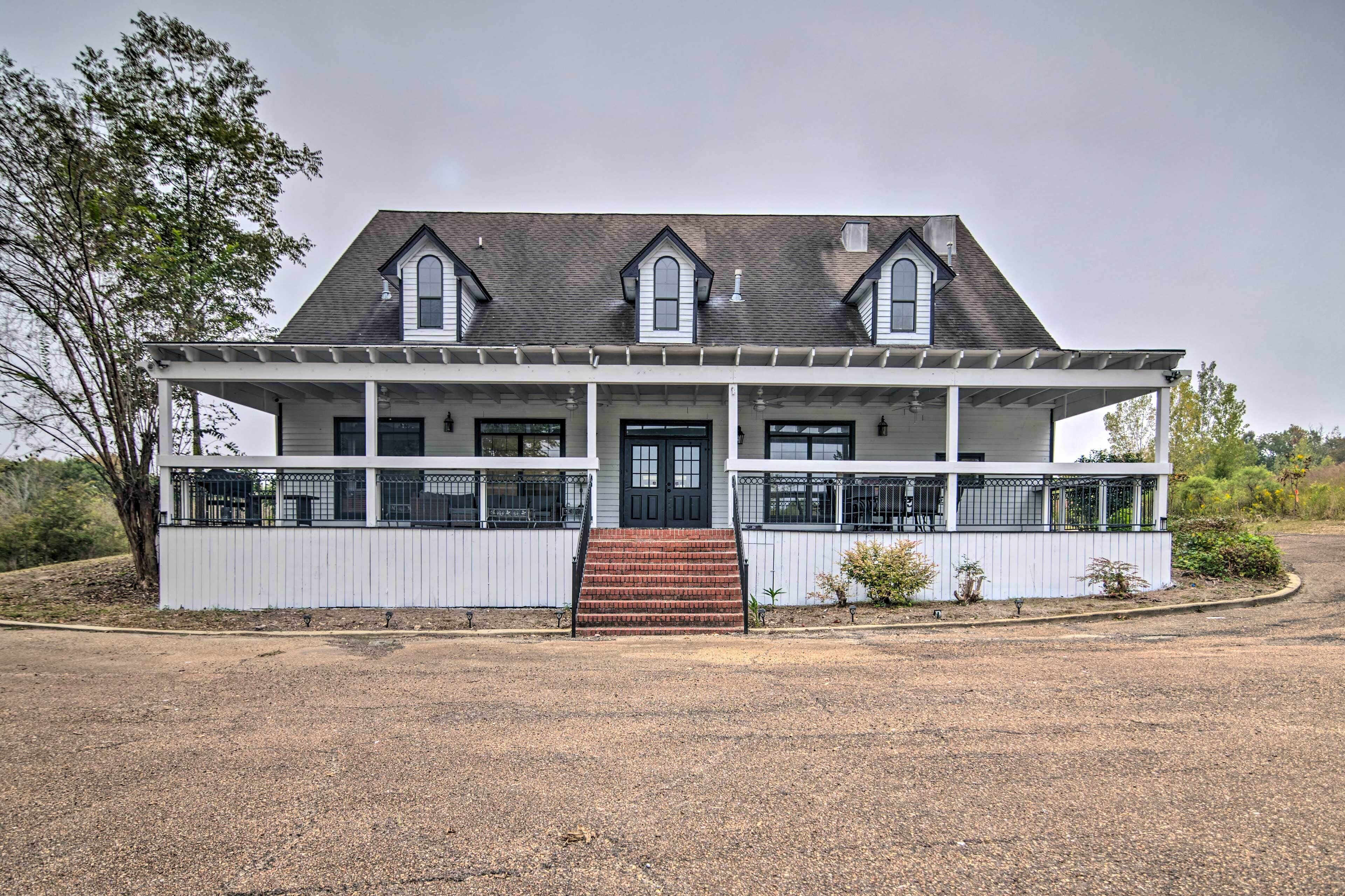 A two-story house with a front porch, a central door, and a small front yard.