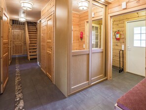 A wooden interior hallway with a staircase, doors, and a fire extinguisher.