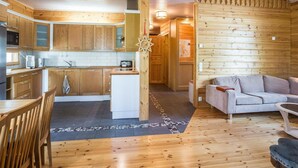 Interno di una baita di legno con cucina, zona pranzo e soggiorno.