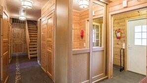 Un interno in legno con un corridoio centrale, porte di legno e un estintore a parete.