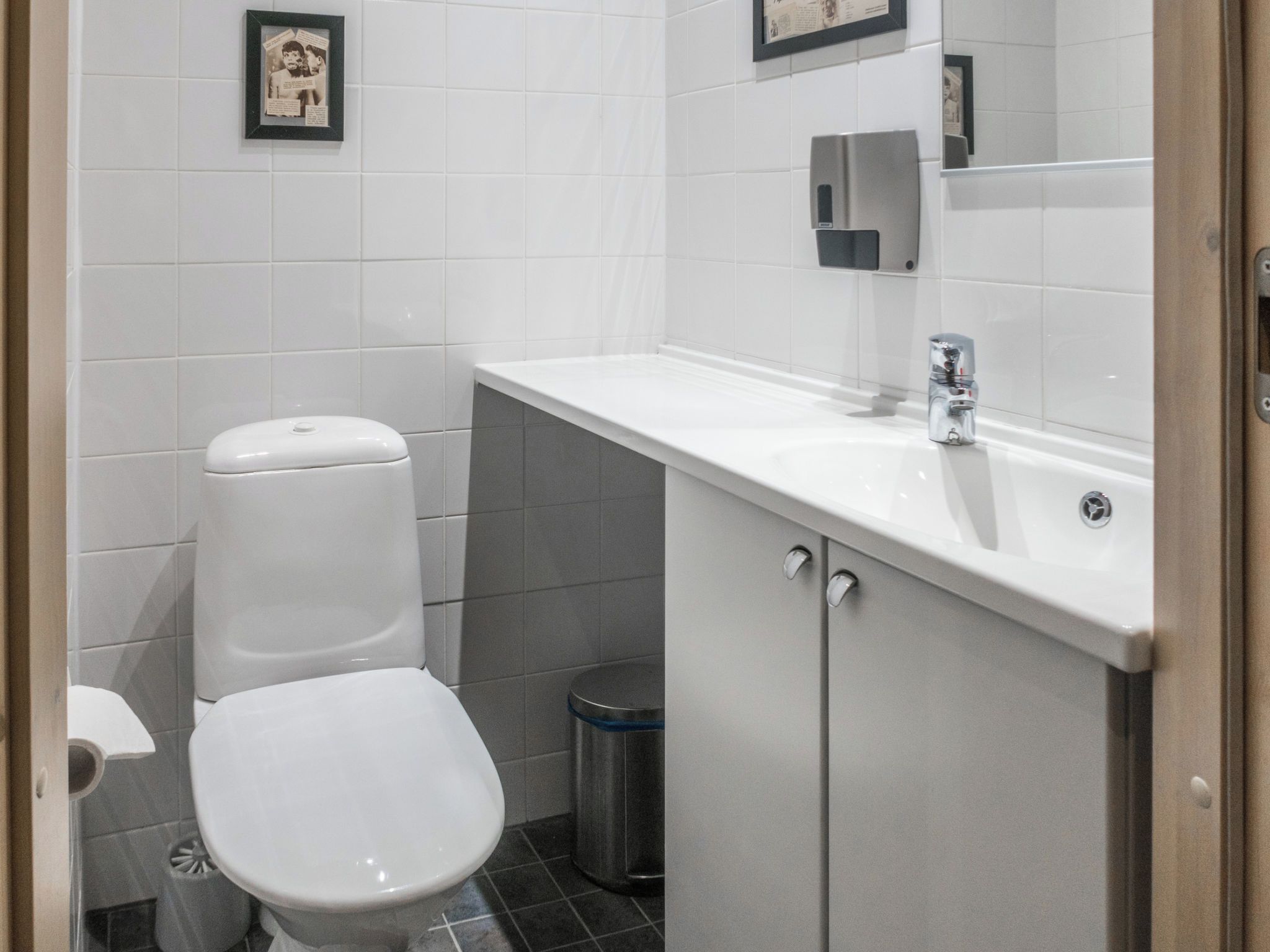 A small, modern bathroom with a white toilet, a sink, and a trash bin.