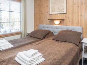 Une chambre d’hôtel avec deux lits, une fenêtre avec des stores, une carte accrochée au mur et une table de chevet avec des serviettes.