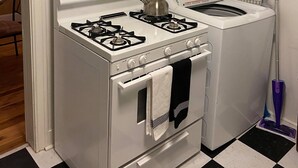 A compact kitchen with a gas stove, oven, and a washing machine. - Cozy Downtown Home (Bryan)