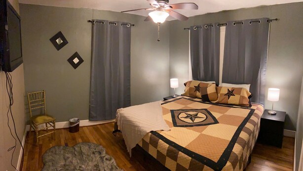 A bedroom with a bed, two bedside lamps, a ceiling fan, and a chair. - Cozy Downtown Home (Bryan)