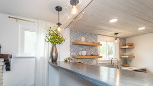 Una cocina moderna con una isla central, iluminación colgante y un backsplash con diseño.