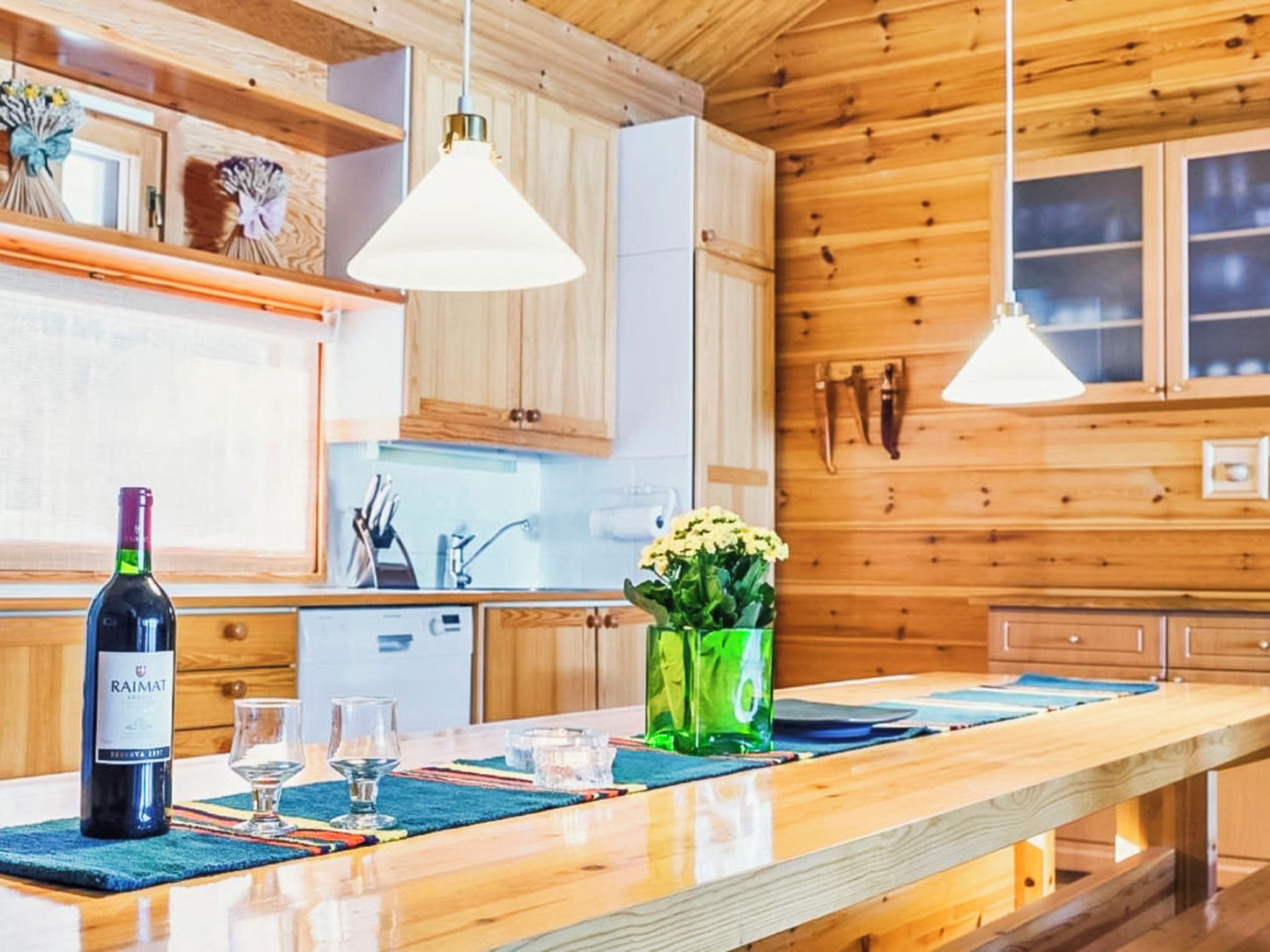 Una cucina moderna con mobili in legno, un'isola centrale con un vaso di fiori e luci a sospensione.