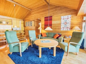A cozy cabin interior with a wooden ceiling, a round wooden coffee table, and a blue rug. - Sinikuono by Interhome (Ylläsjärvi)