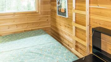 A wooden cabin room with a bed, a window, and a poster on the wall.