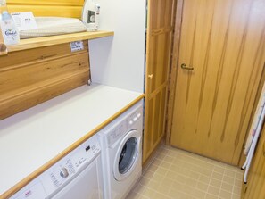 A laundry area with a washing machine, a shelf with a bottle of Comfort laundry detergent, and a wooden door. - Sinikuono by Interhome (Ylläsjärvi)