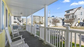 A covered porch with white railings, outdoor seating, and a view of a residential street. - Prime Location Close to the Beach and Boardwalk (Ocean City)