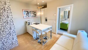 Een moderne keuken met een wit aanrechtblad, een hanglamp en een kunstwerk in een lijst aan de muur.