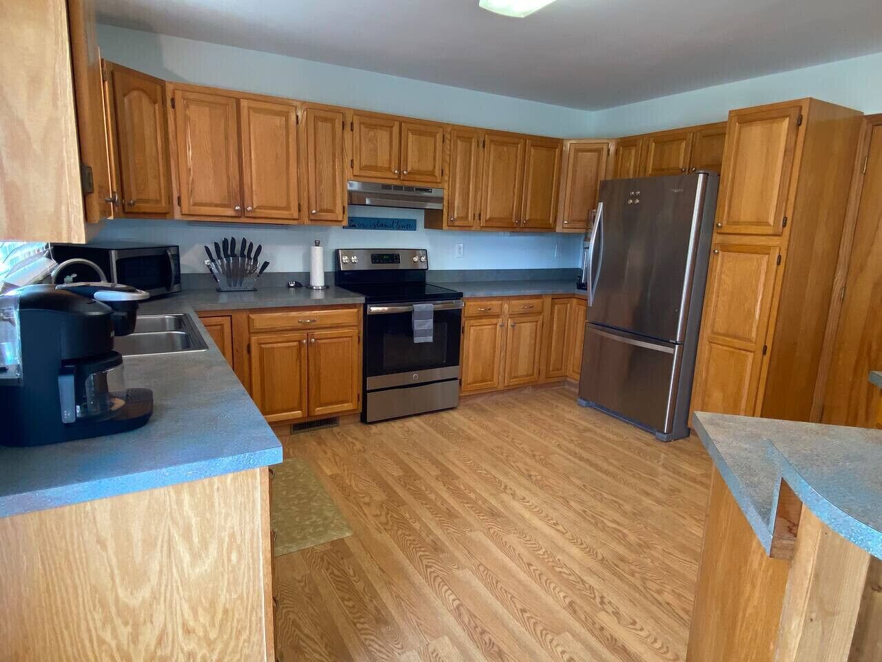 A kitchen with wooden cabinets, a stainless steel refrigerator, a microwave, and a coffee maker.