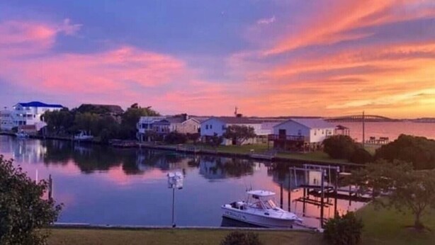 A waterfront property with a dock, a boat, and a row of houses. - Island Haven - Hot Tub & Beautiful Water Views (Nags Head)