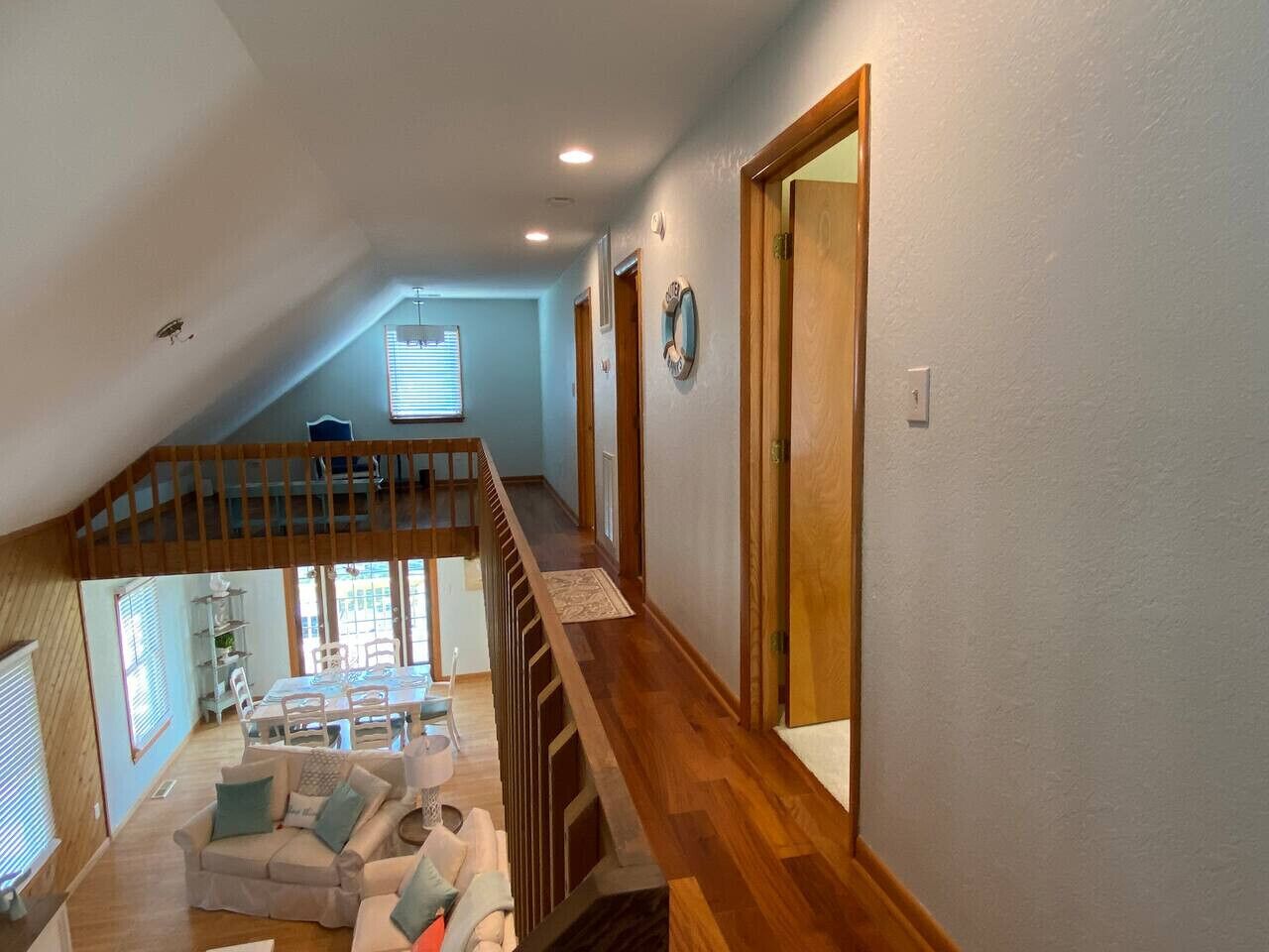 Un vaste espace de vie aménagé dans un style loft, avec un escalier en bois, un coin repas et une vue sur l’extérieur.