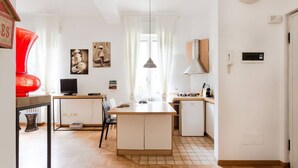 A modern kitchen with a central island, a dining area with chairs, and a television. - Washington Cosy and Comfortable Apartment (Milano)