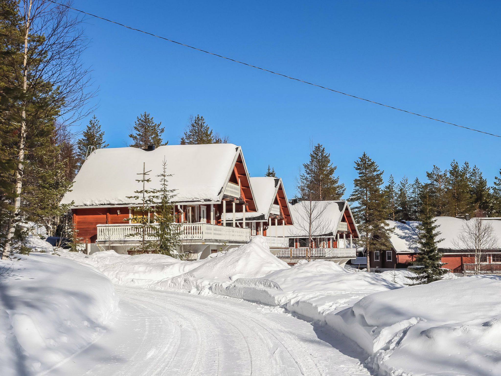 A snow-covered landscape with a row of cabins featuring red roofs and white exteriors.