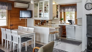 Un espacio habitable compacto con comedor, cocina y televisor montado en la pared.