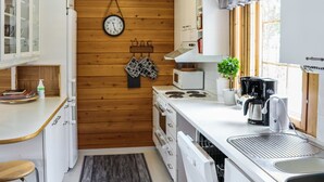 Cocina compacta con paredes de madera, un reloj, un microondas, una cafetera y un lavamanos.