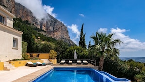 Una piscina con sedie a sdraio e montagne sullo sfondo.