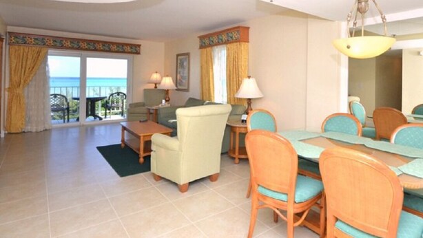 Una habitación de hotel con balcón, comedor y sala de estar.