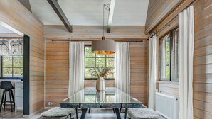 A dining area with a long table, benches, and a hanging light fixture.