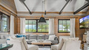 A spacious living room with a large sofa set, a coffee table, and a television mounted on the wall.