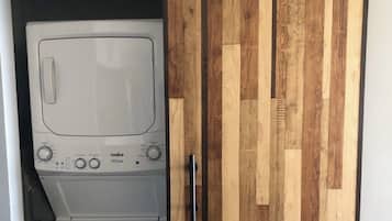 Une buanderie équipée d’un lave-linge et d’un sèche-linge, avec une porte coulissante en bois et une poignée en métal.