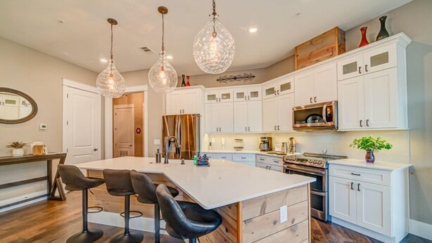 A modern kitchen with a large island, white cabinetry, and pendant lighting.