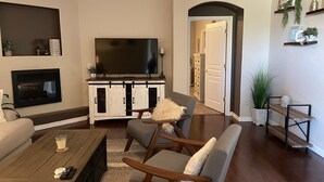 A living room with a TV, sofa, coffee table, and a fireplace.
